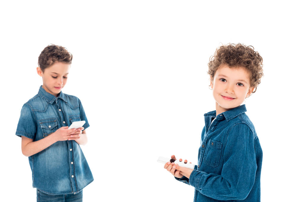 duas crianças em camisas jeans usando smartphones isolados em branco
 - Foto, Imagem