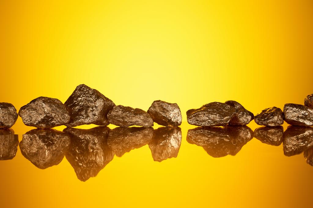 zlaté lesklé texturované kameny s odrazem a žlutým zadním světlem  - Fotografie, Obrázek