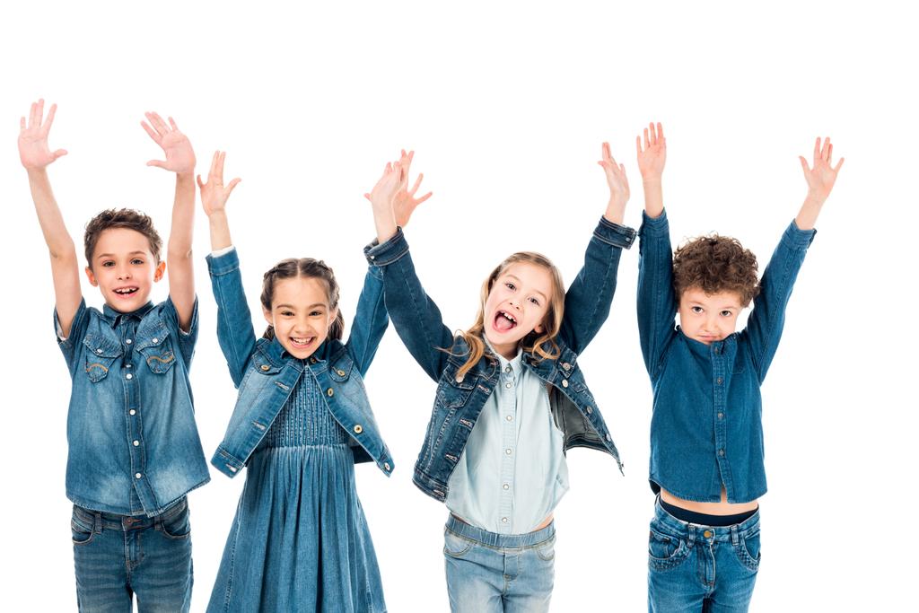 vista frontal de cuatro niños en ropa de mezclilla sonriendo con las manos arriba aislados en blanco
 - Foto, imagen