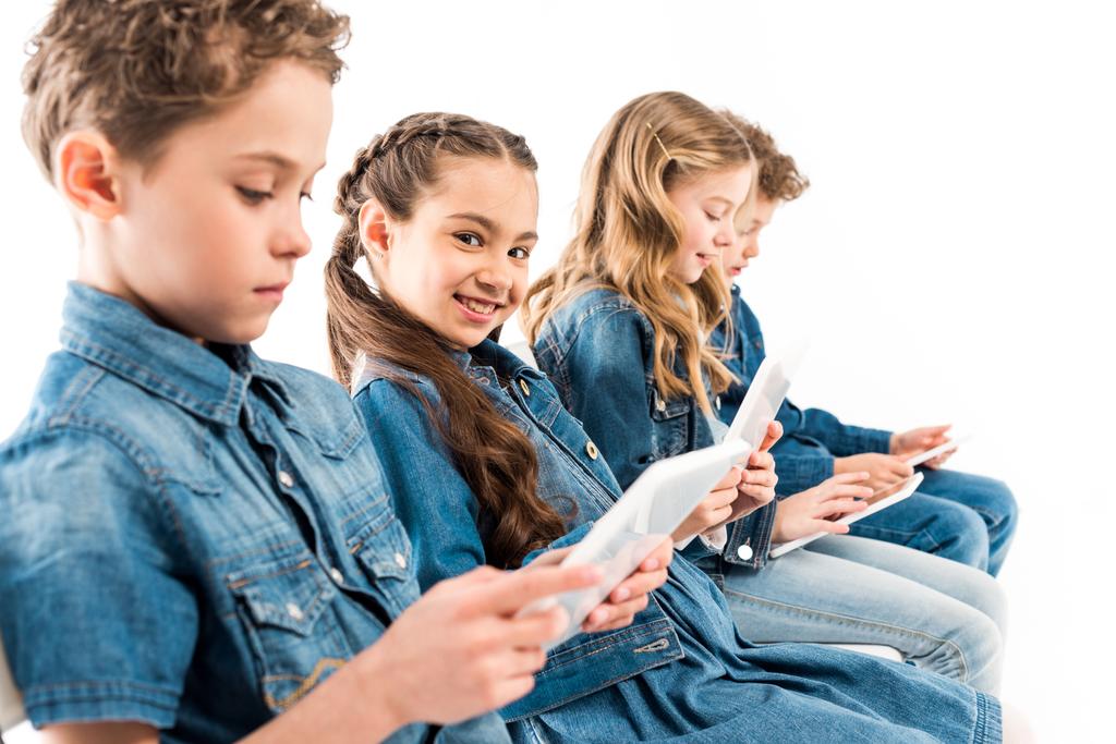 селективный фокус четырех детей, использующих цифровые таблетки, изолированные на белом
 - Фото, изображение