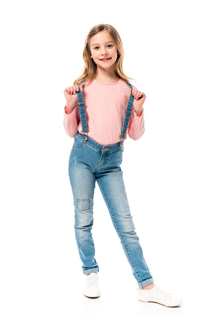 visão de comprimento total da criança em jeans olhando para a câmera com sorriso isolado no branco
 - Foto, Imagem