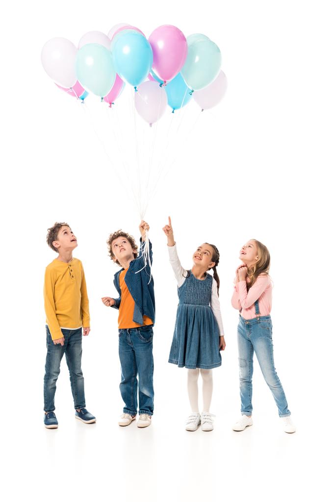 Ganzkörperansicht von vier Kindern mit Luftballons auf weißem Grund - Foto, Bild