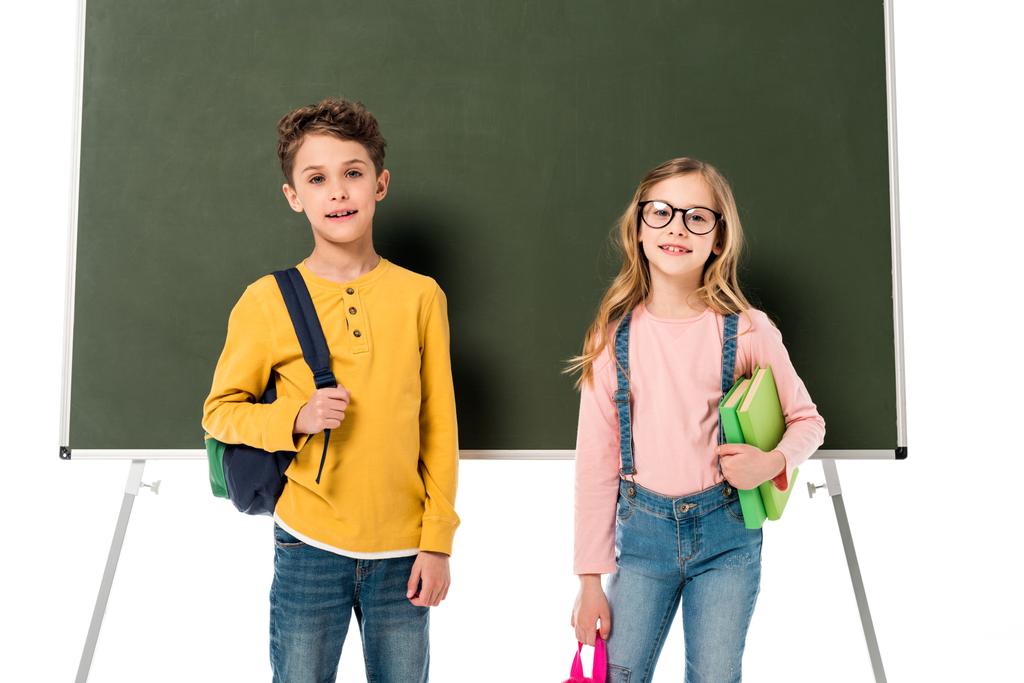 дві школярі з рюкзаками і книгами, що стоять біля дошки, ізольовані на білому
 - Фото, зображення