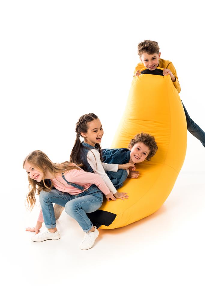 čtyři děti, které si hrají s fazolovou židlí na bílém - Fotografie, Obrázek