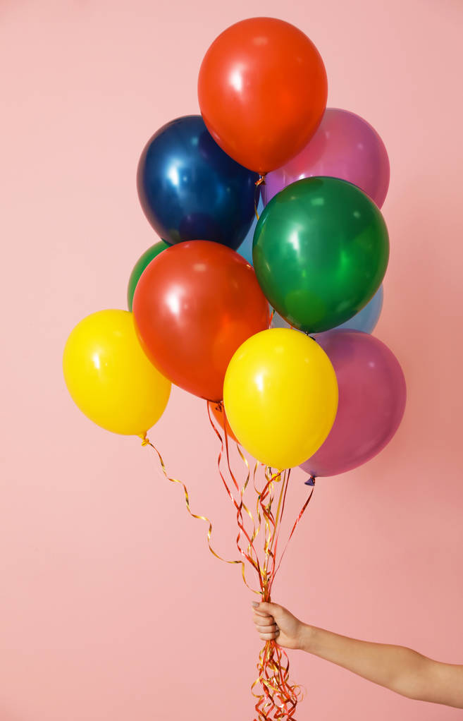 Mujer sosteniendo racimo de globos brillantes sobre fondo de color, primer plano. Tiempo de celebración
 - Foto, Imagen