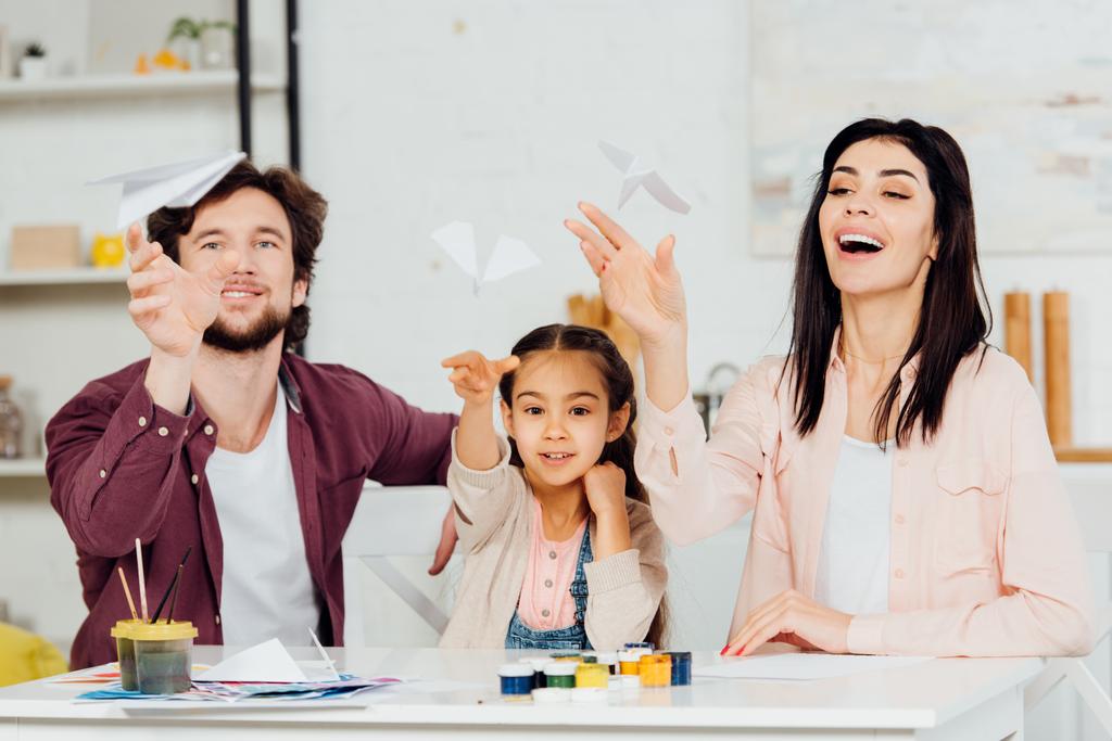 вибірковий фокус щасливої сім'ї, дивлячись на літаючі паперові площини вдома
  - Фото, зображення