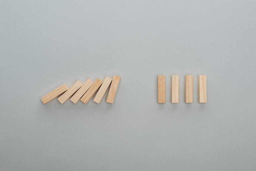 bovenaanzicht van vallende houten blokken geïsoleerd op grijs, domino effect concept - Foto, afbeelding