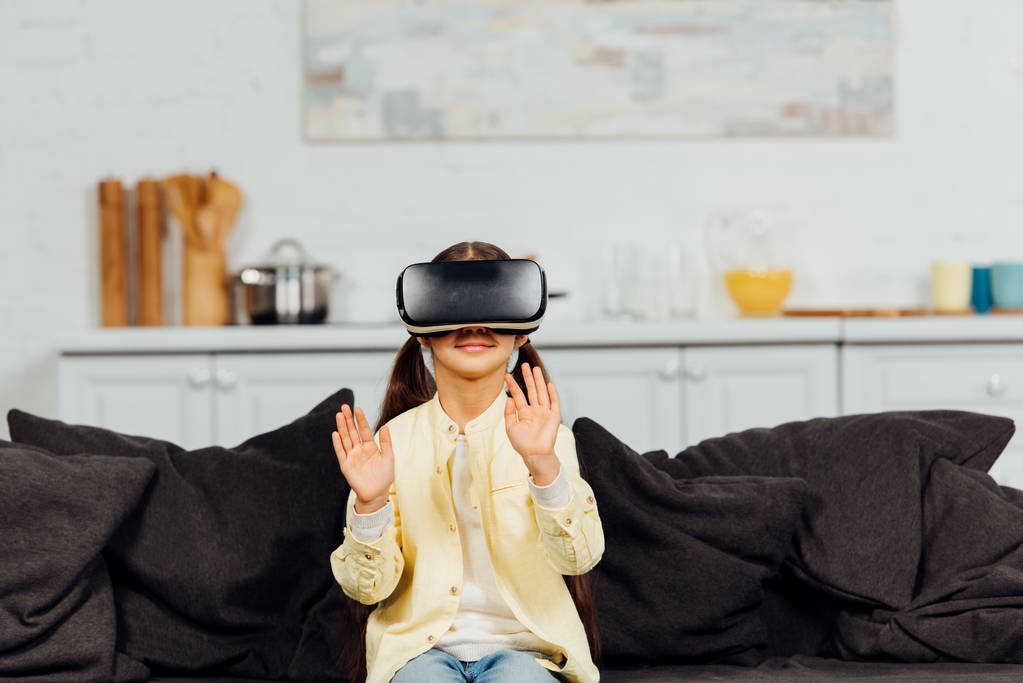 cheerful kid gesturing while wearing virtual reality headset at home  - Photo, Image