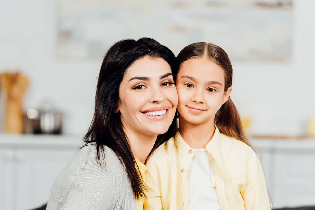 happy child looking at camera with cheerful mother at home  - Photo, Image