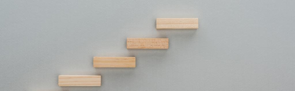 πανοραμική βολή από ξύλινα τουβλάκια που συμβολίζουν τη σκάλα καριέρας που απομονώνεται σε γκρι - Φωτογραφία, εικόνα