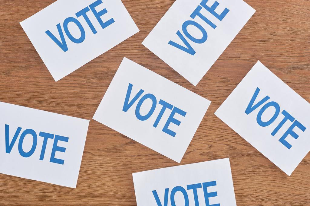 vue du dessus des cartes blanches avec lettrage de vote bleu éparpillé sur la table en bois
 - Photo, image