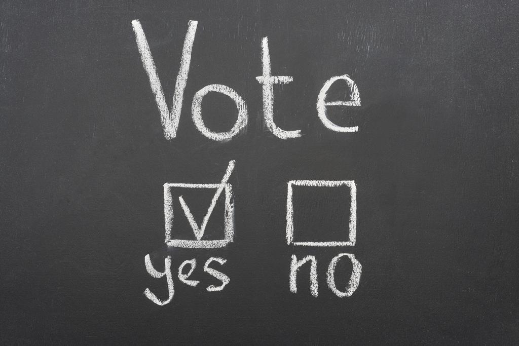 黒い黒板の「はい」の単語の近くに白い投票レタリングとチェックマークのトップビュー - 写真・画像