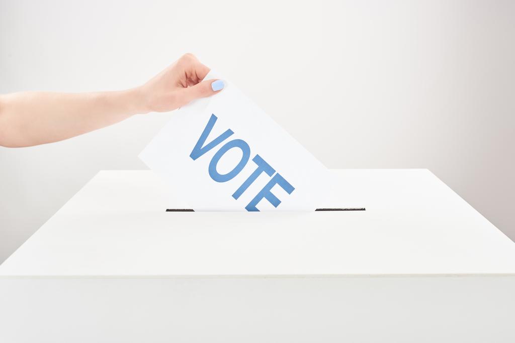 partial view of woman putting vote in box on grey background - Photo, Image