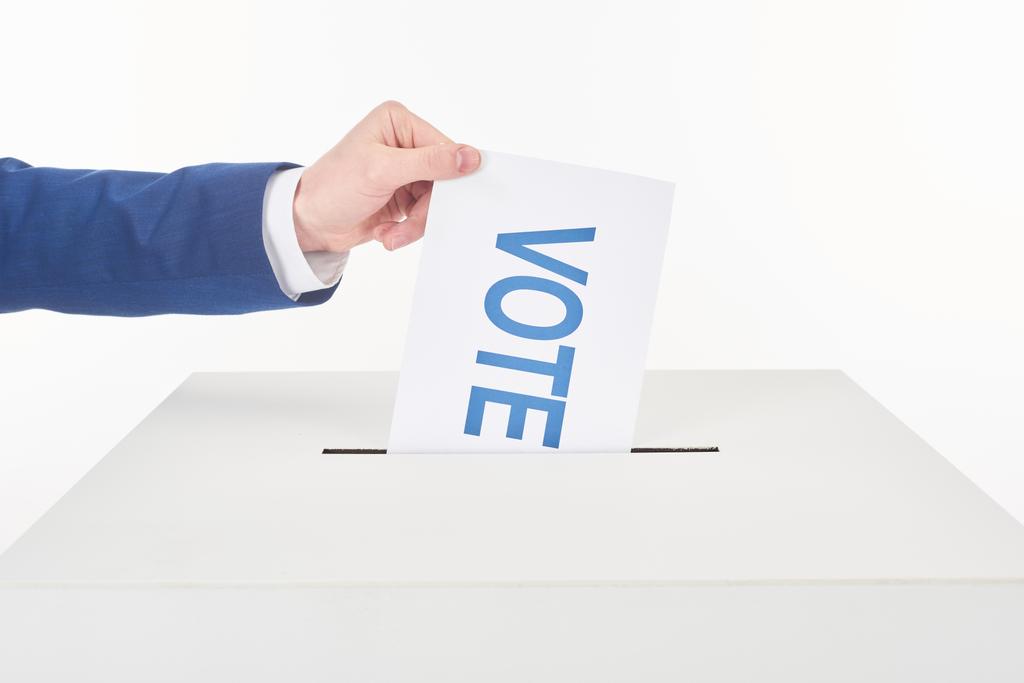 abgeschnittene Ansicht eines Mannes, der Karte mit Stimmabgabe in Schachtel legt, isoliert auf weiß - Foto, Bild