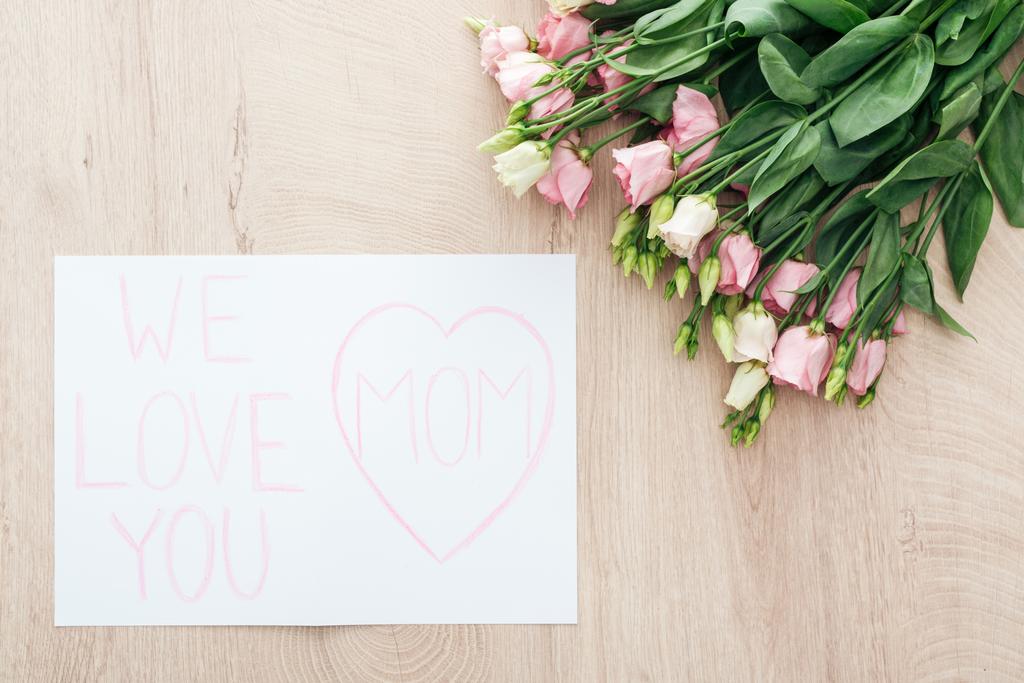 felülnézet eustoma virágok és kártya szeretjük anyu köszöntő a fából készült asztal - Fotó, kép