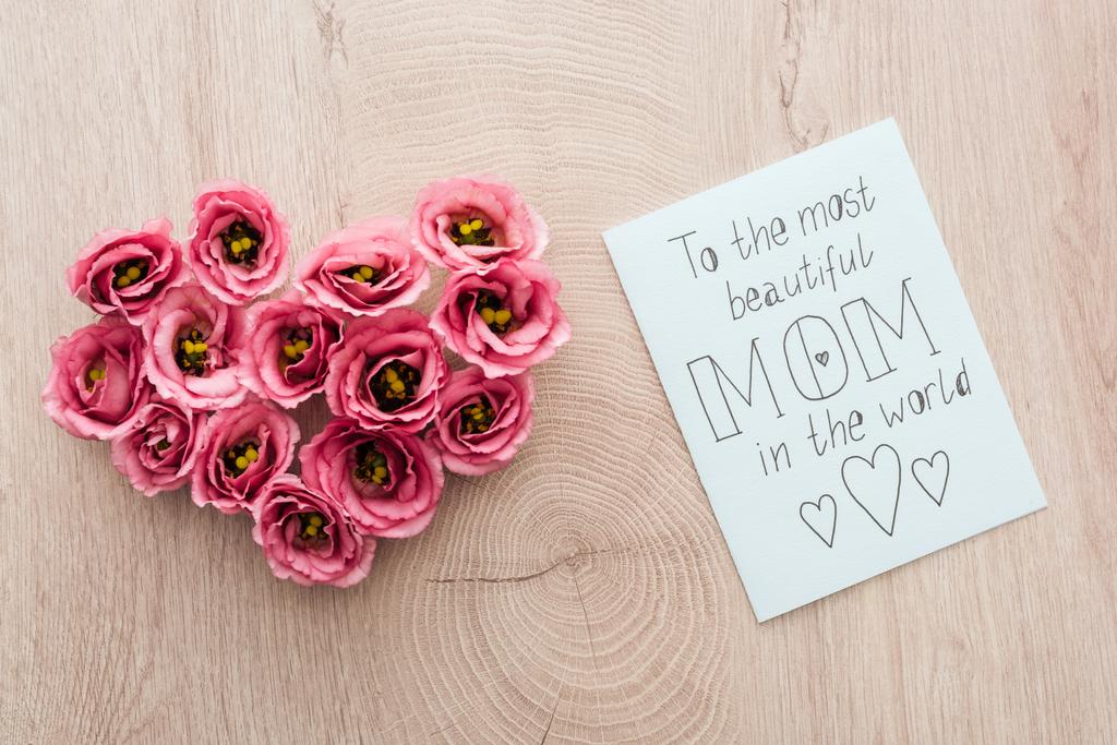 top view of heart sign made of eustoma flowers and card with to the most beautiful mom in the world lettering on wooden table - Photo, Image