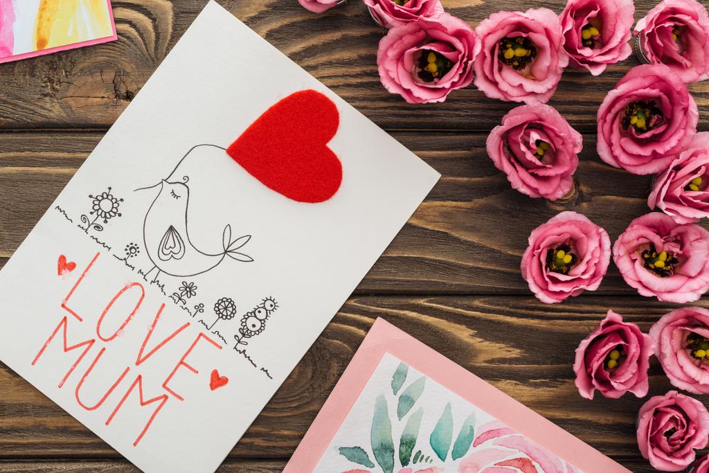 κορυφή θέα της ευστόμα λουλούδια και κάρτα με την αγάπη μαμά γράμματα σε ξύλινο τραπέζι - Φωτογραφία, εικόνα