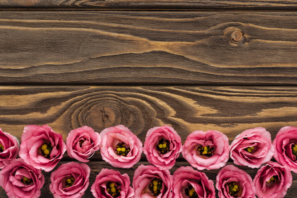 Draufsicht auf arrangierte rosa Eustoma-Blumen auf Holztisch mit Kopierraum - Foto, Bild