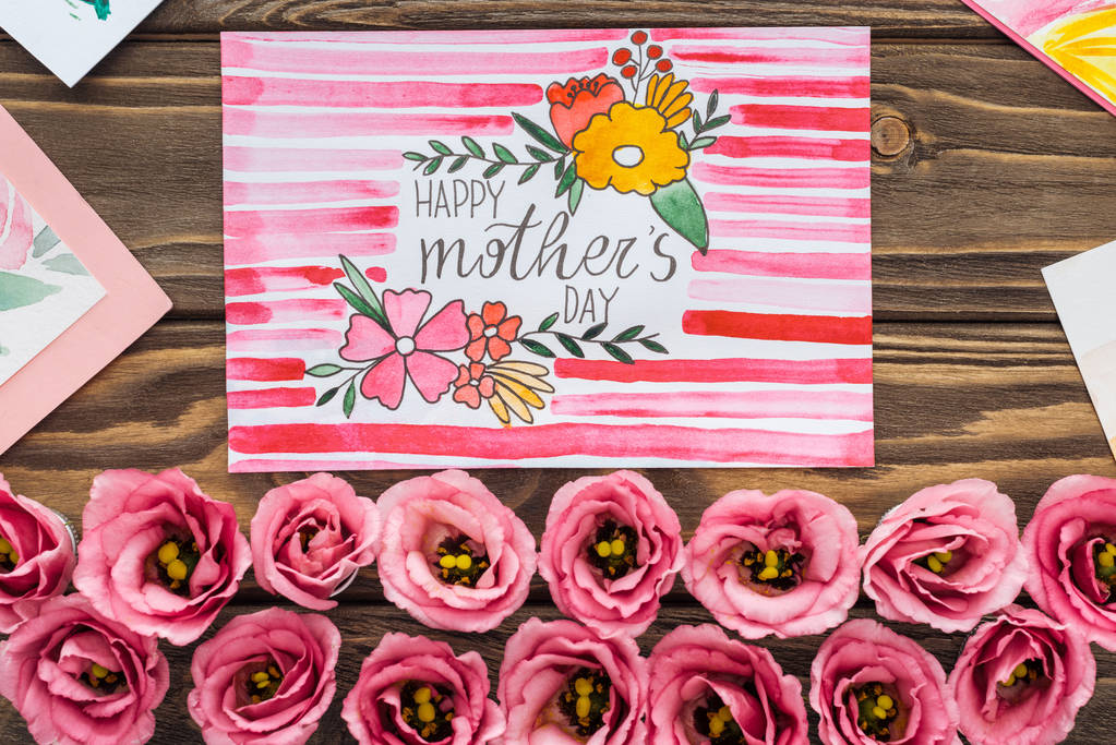 ahşap masada mutlu anneler günü tebrik ile eustoma çiçek ve kart üst görünümü - Fotoğraf, Görsel