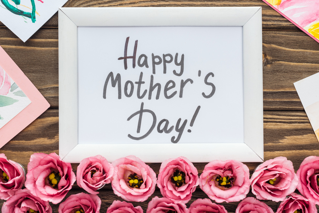 Top weergave van kaarten, frame met Happy Mothers Day belettering en roze Eustoma bloemen op houten tafel - Foto, afbeelding