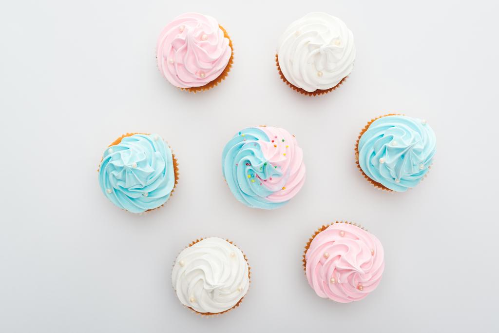 ylhäältä näkymä herkullisia valkoinen, vaaleanpunainen ja sininen cupcakes strösselit eristetty valkoinen
 - Valokuva, kuva