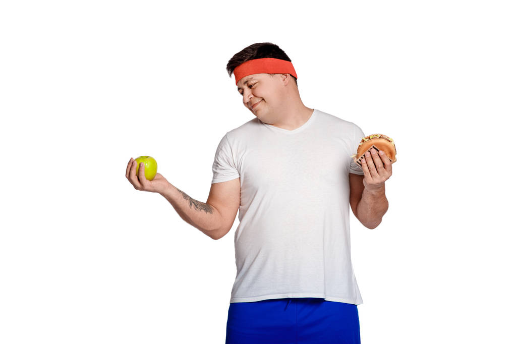 Grasso uomo non può scegliere tra un hamburger e una mela
. - Foto, immagini