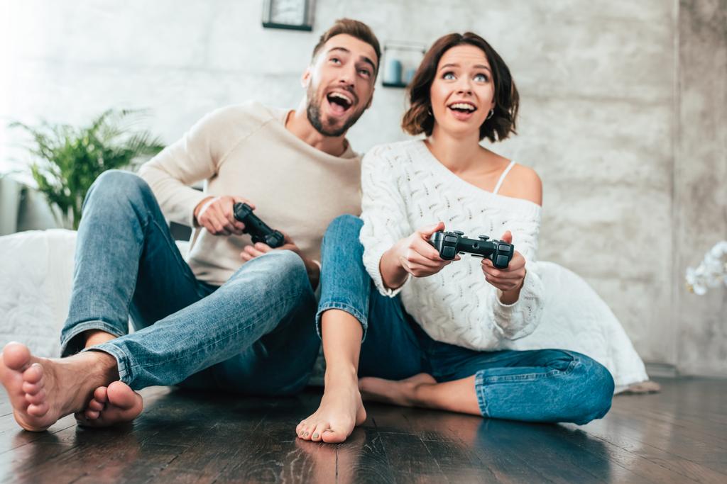 χαμηλή γωνία θέα του ευτυχισμένο άνθρωπο και γυναίκα παίζοντας βίντεο παιχνίδι στο σπίτι  - Φωτογραφία, εικόνα