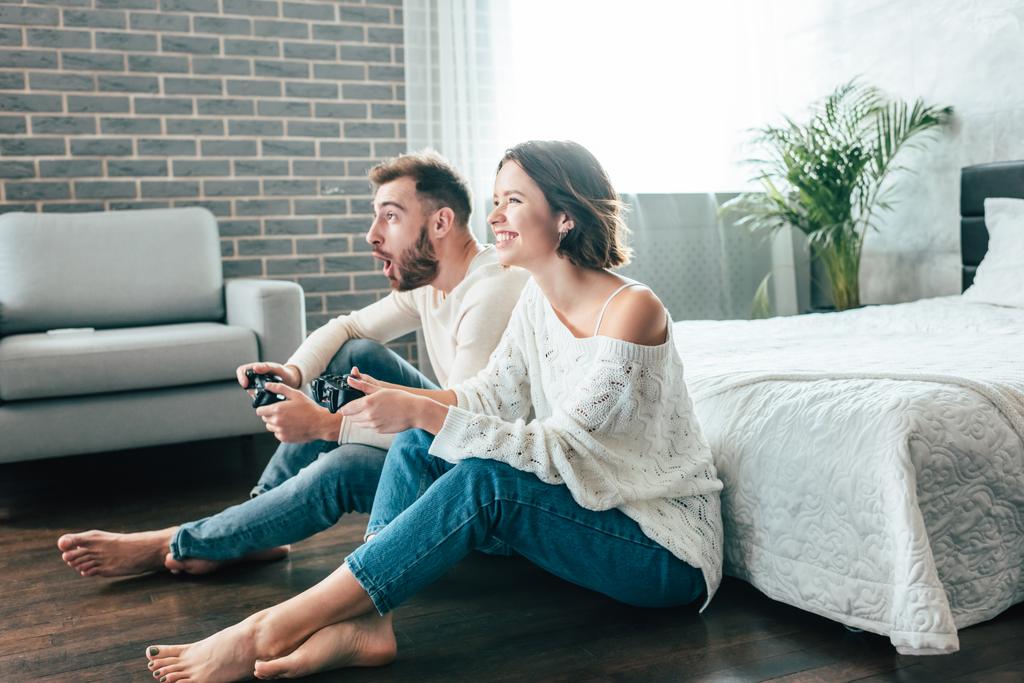 счастливая женщина и эмоциональный мужчина играют в видеоигру дома
  - Фото, изображение