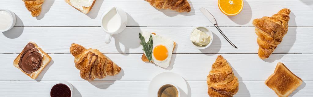 panoráma lövés édes croissant a közelben pirítós és italok fehér  - Fotó, kép