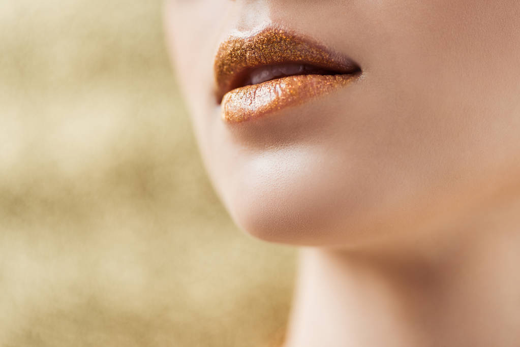 vue recadrée de jeune femme aux lèvres dorées et brillantes
 - Photo, image