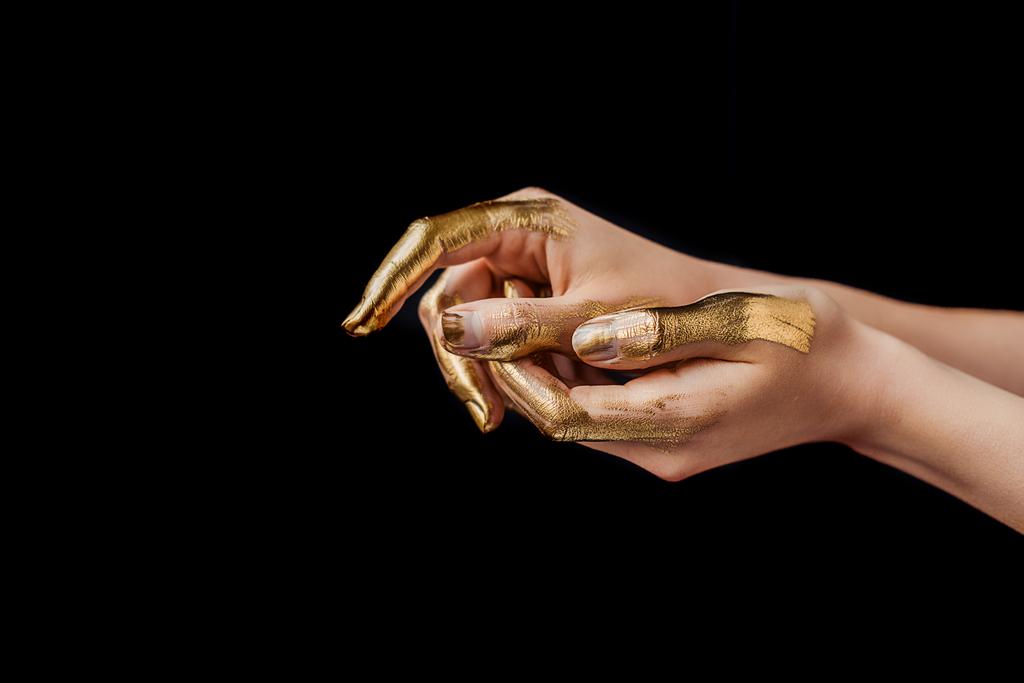 Ausgeschnittene Ansicht weiblicher Hände in Gold isoliert auf Schwarz gemalt - Foto, Bild