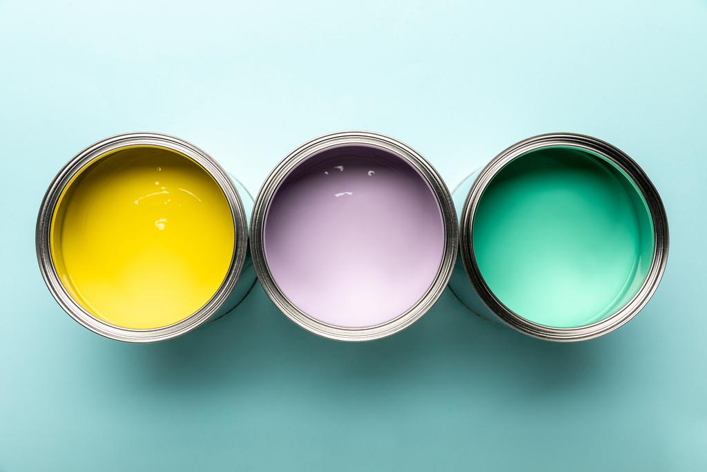 Draufsicht auf drei Dosen mit Farben auf blauer Oberfläche - Foto, Bild