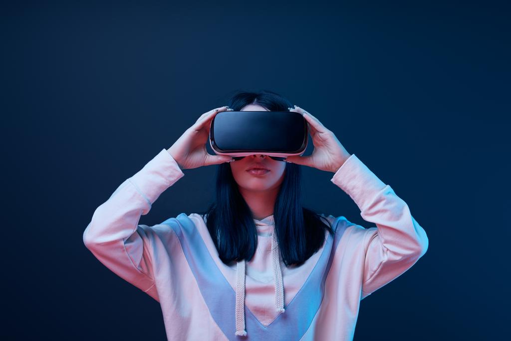 брюнетка молодая женщина касаясь гарнитуры виртуальной реальности на синий
  - Фото, изображение