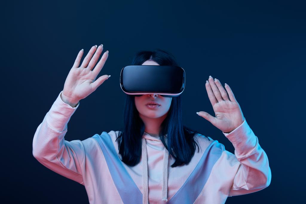 jeune femme brune portant casque de réalité virtuelle et geste sur bleu
  - Photo, image