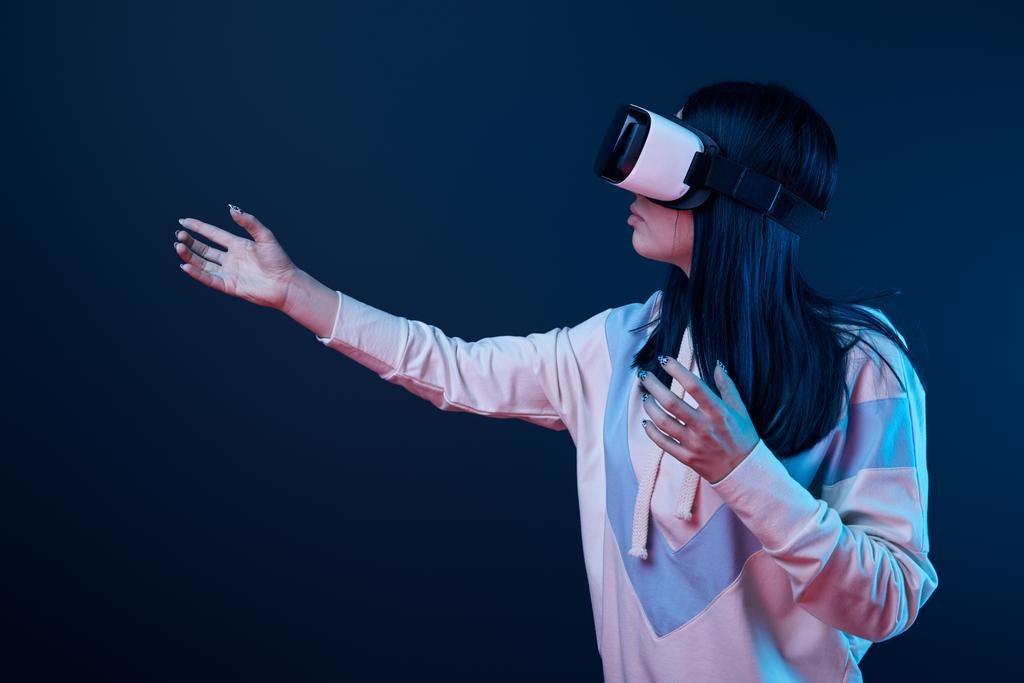 brunette fille portant la réalité virtuelle casque et geste sur bleu
 - Photo, image