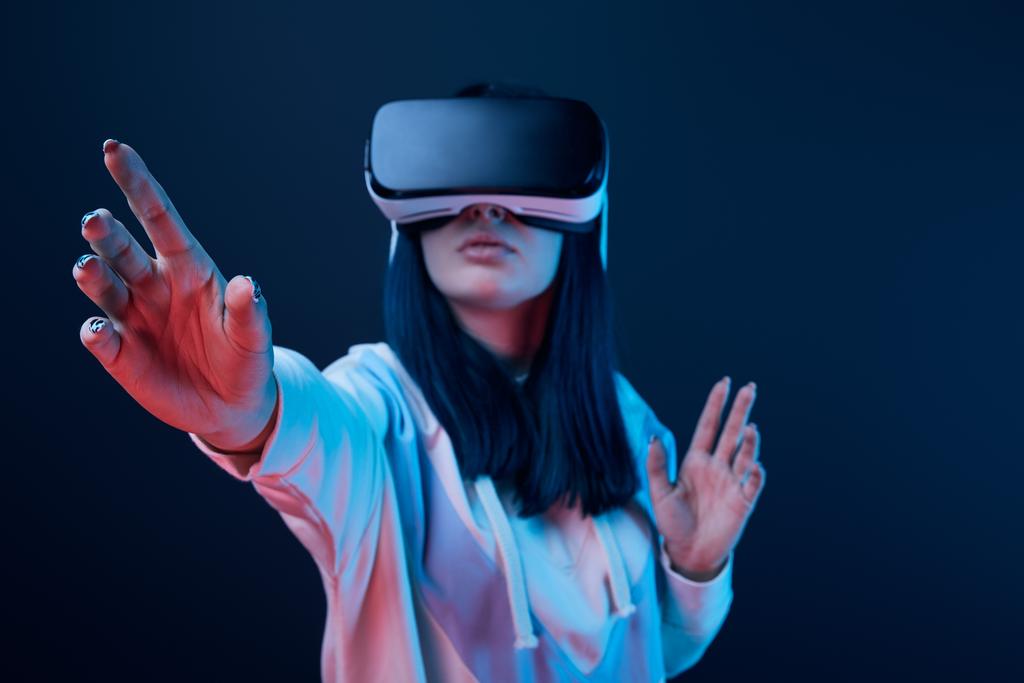 selective focus of young woman gesturing while using virtual reality headset on blue  - Photo, Image