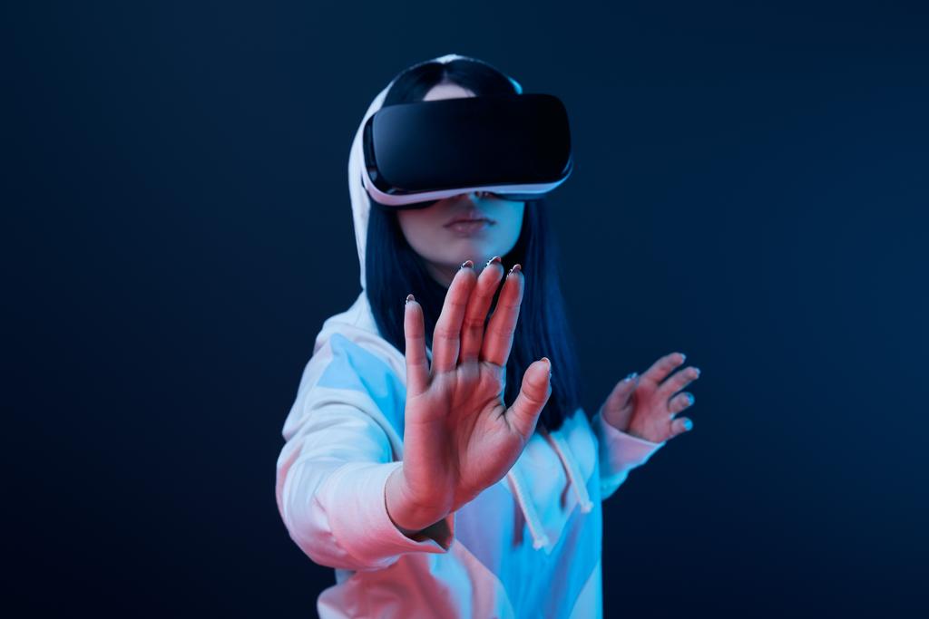 messa a fuoco selettiva della gestualità femminile durante l'utilizzo di cuffie realtà virtuale sul blu
  - Foto, immagini