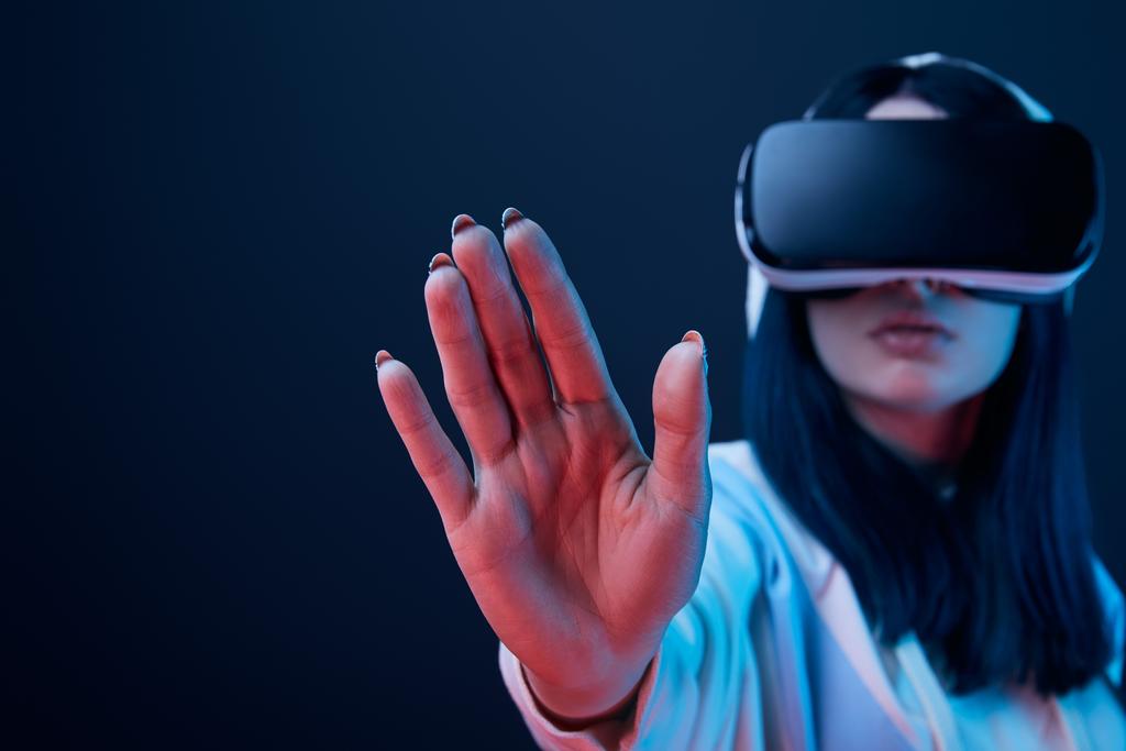 enfoque selectivo de la mano de la chica con auriculares de realidad virtual y el gesto en azul
  - Foto, Imagen