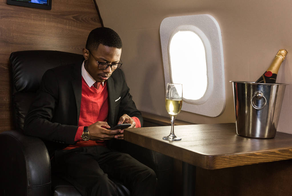 Exitoso joven afroamericano hombre de negocios negro sentado en la silla de su jet privado
 - Foto, Imagen