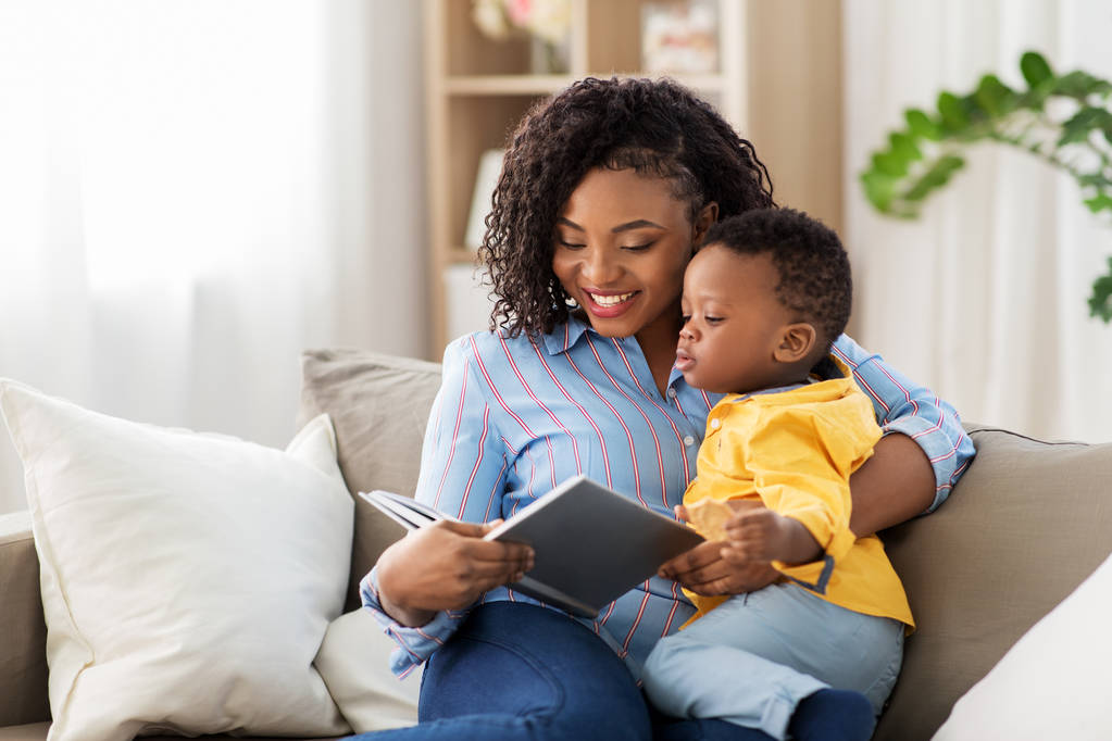 evde kitap ve bebek ile afrikalı-amerikalı anne - Fotoğraf, Görsel