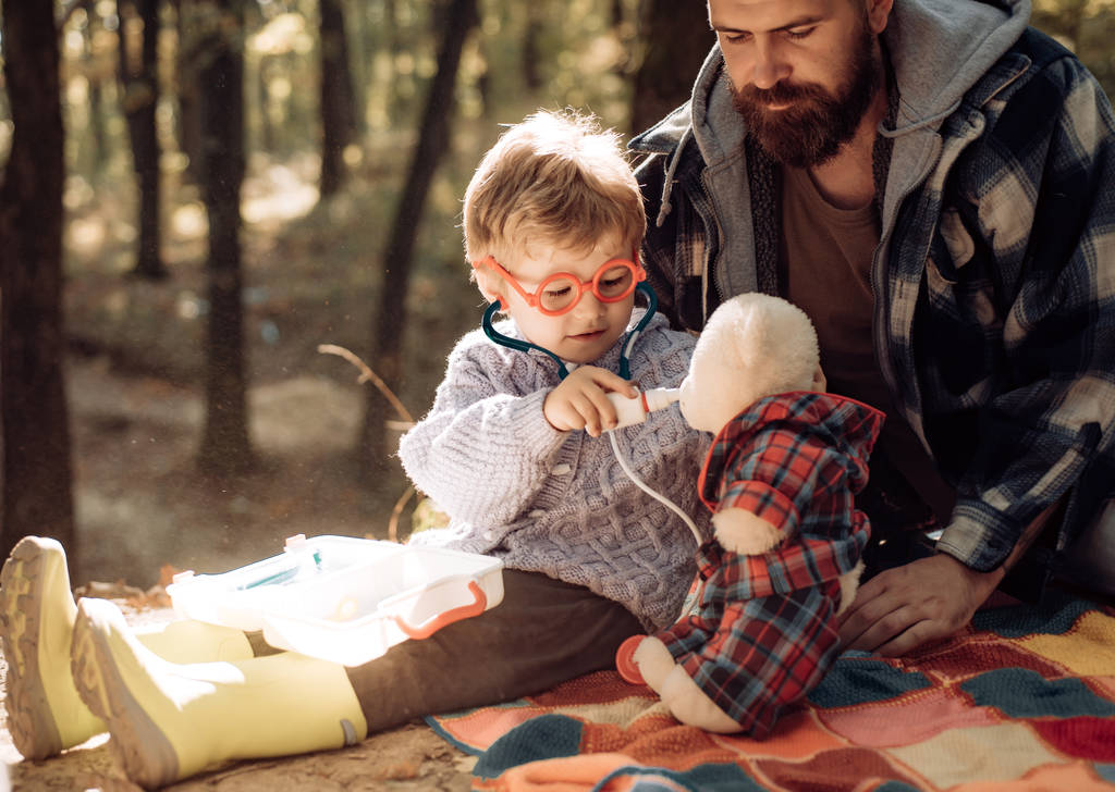 Χαριτωμένο αγόρι με υαλοκαθαριστήρα κοντά φθινόπωρο δέντρο. Πατέρας και παιδί γιος στο φθινοπωρινό πάρκο να διασκεδάζει και να γελάει. Ευτυχισμένη οικογένεια, πατέρας και μωρό γιος που παίζει και γελάει στο φθινοπωρινό περπάτημα. - Φωτογραφία, εικόνα