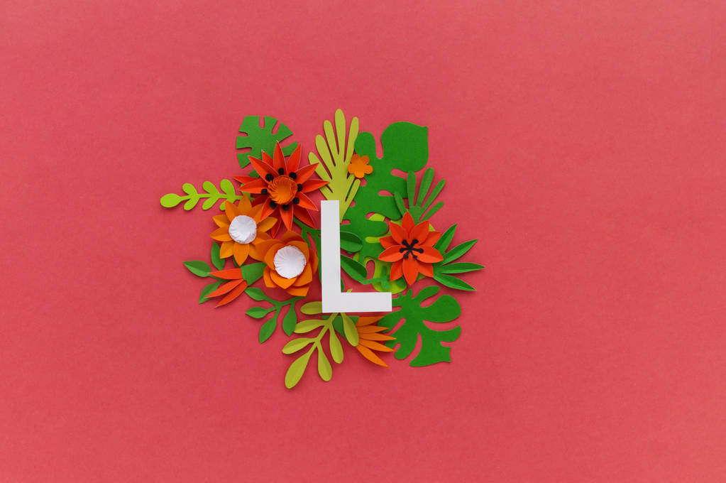 літера L алфавіту вирізана з білого паперу, оточена тропічними квітами. Рожевий фон
. - Фото, зображення