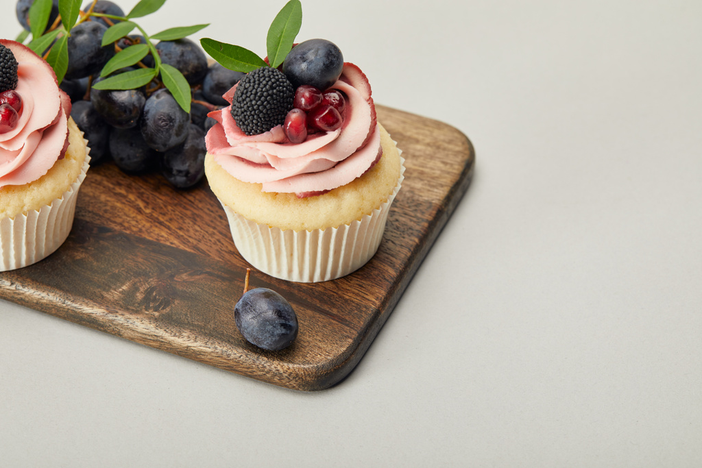 planche à découper en bois avec cupcakes sucrés isolés sur gris
 - Photo, image