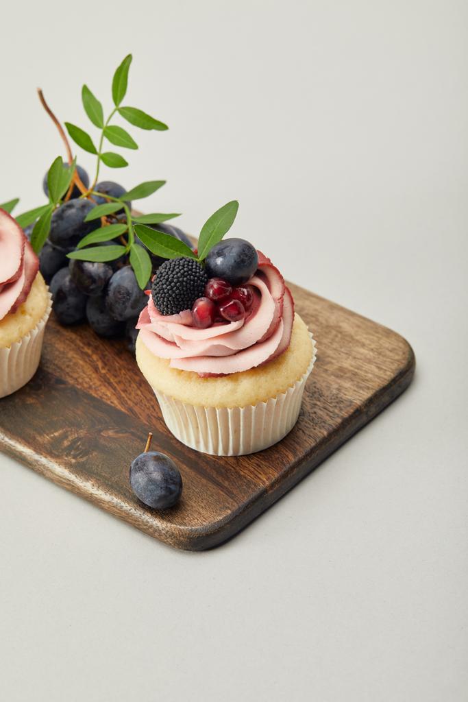 cupcakes és szőlő a vágódeszka izolált szürke - Fotó, kép