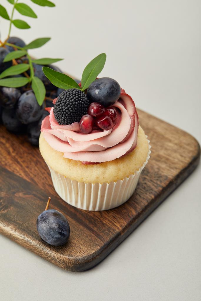 cupcake con crema e uva su tagliere isolato su grigio
 - Foto, immagini