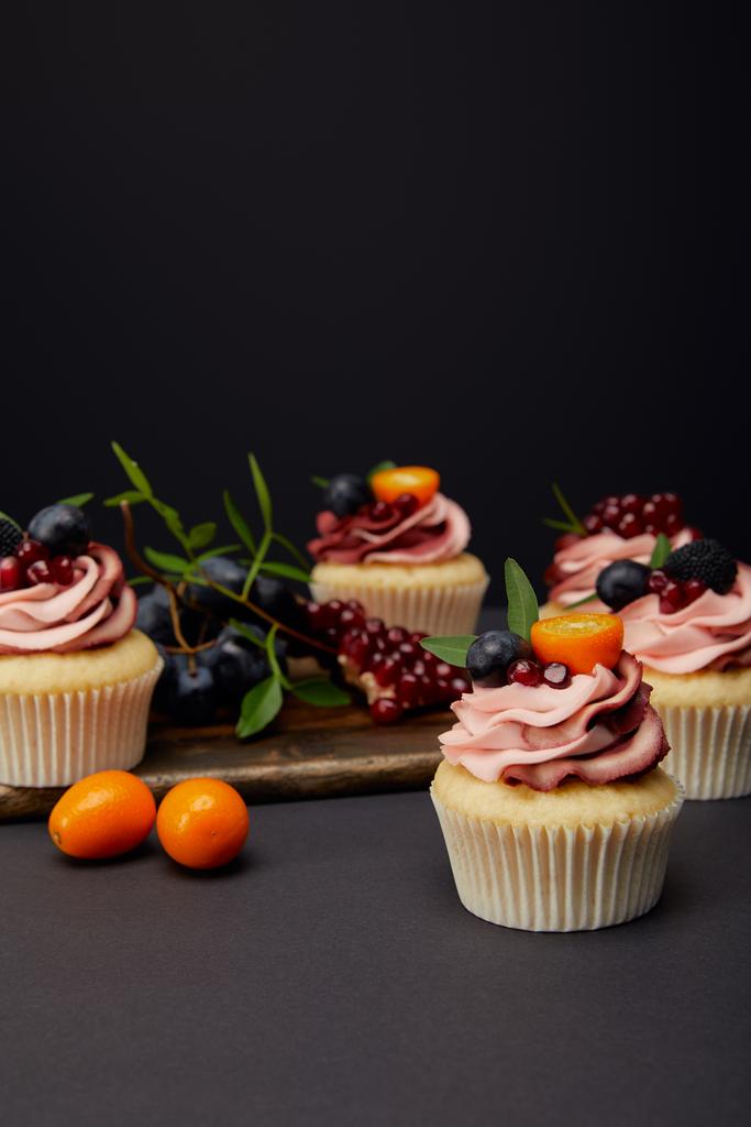 dorty se smetanou, ovocem a bobulovinami na šedé ploše izolované černě - Fotografie, Obrázek