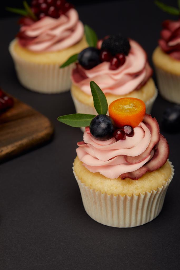 siyah yüzeyde meyve ve çilek ile cupcakes - Fotoğraf, Görsel