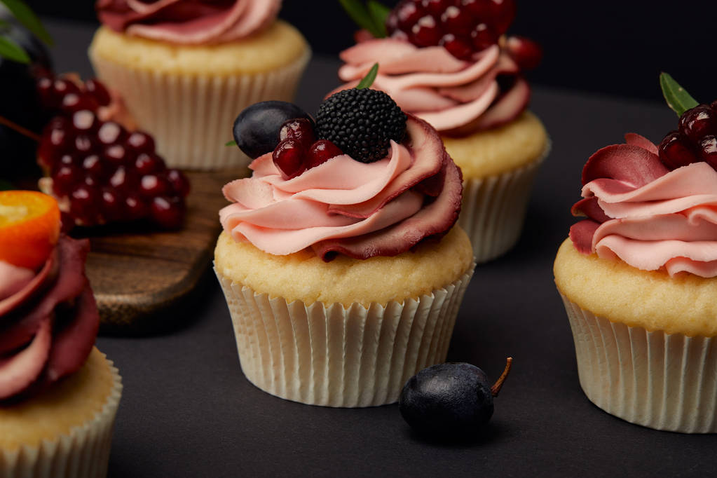 Cupcakes met vruchten en bessen op zwart oppervlak - Foto, afbeelding