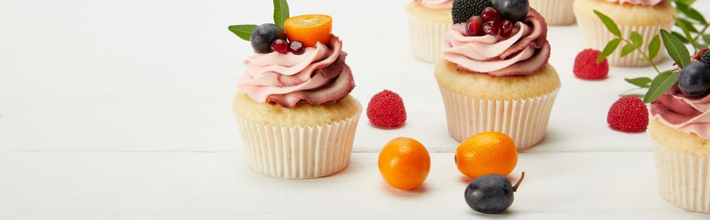 白い表面に果物やベリーとカップケーキのパノラマショット - 写真・画像