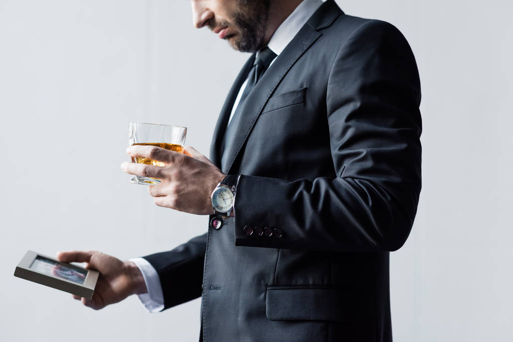 részleges kilátás az ember a ruha gazdaság üveg whisky és fotó keretben - Fotó, kép